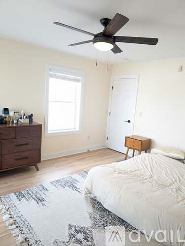 A bedroom with a bed, dresser, and window.
