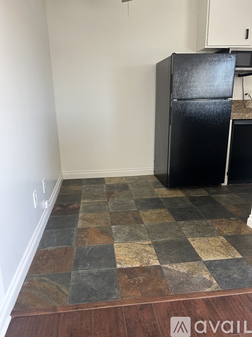 A black fridge in a kitchen with a checkered floor.