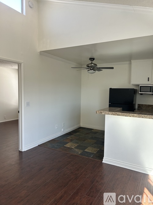 A kitchen with a fan on the ceiling and a microwave on the counter.