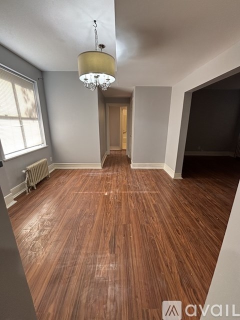 A room with wooden flooring and a chandelier hanging from the ceiling.