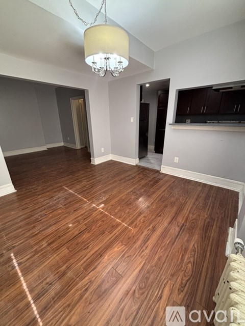 A room with wooden flooring and a chandelier hanging from the ceiling.