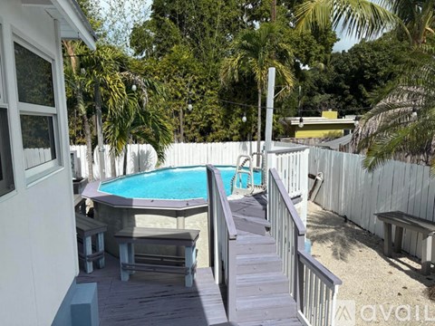 A pool area with a deck and a white fence.
