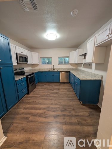 A kitchen with blue cabinets and brown flooring.