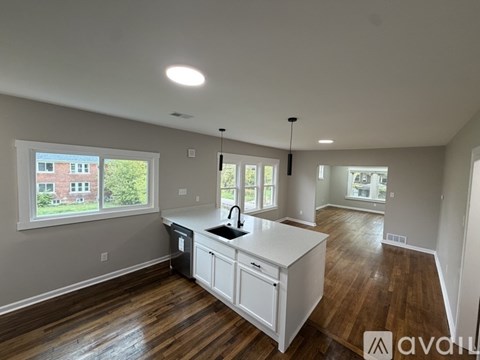 A kitchen with white cabinets and a wooden floor.