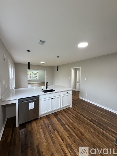A kitchen with white cabinets and a wooden floor.