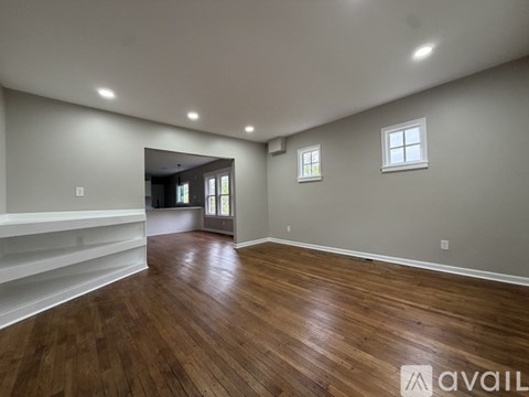 A room with wooden floors and white walls, with a window and a door visible.