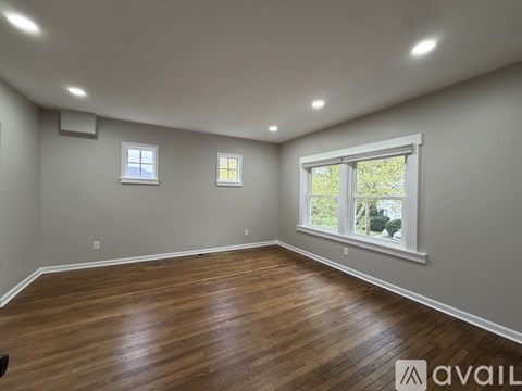 A room with wooden floors and two windows.