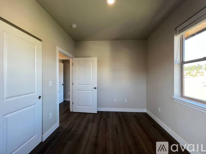 A room with white doors and a window with a view of trees outside.