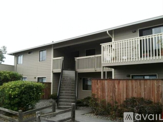 A beige two-story apartment building with a balcony on the second floor.