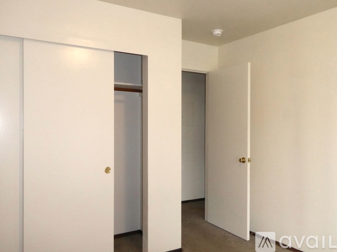 A spacious room with wooden flooring and a central heating vent.