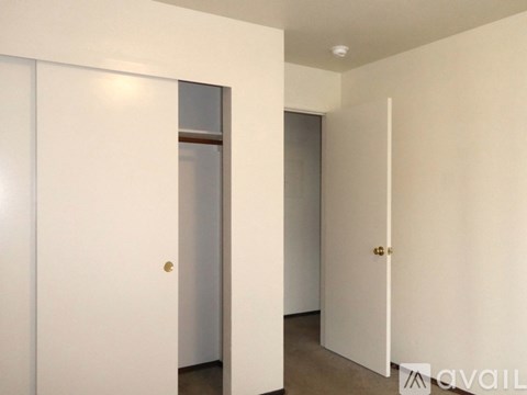 A spacious room with wooden flooring and a central heating vent.