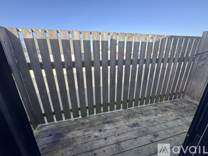A wooden deck with a railing and a clear blue sky in the background.