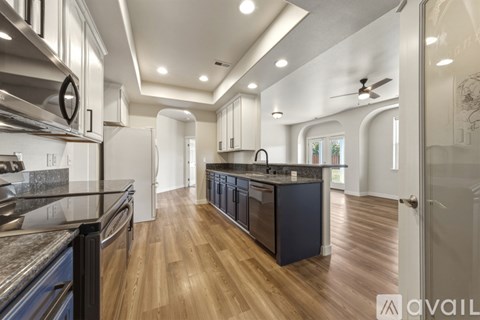 A modern kitchen with dark blue cabinets and wooden floors.