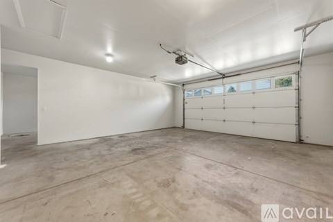 A large empty room with a white ceiling and a window with a view of trees outside.
