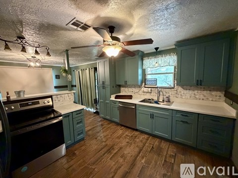 A kitchen with wooden floors and a black stove top oven.