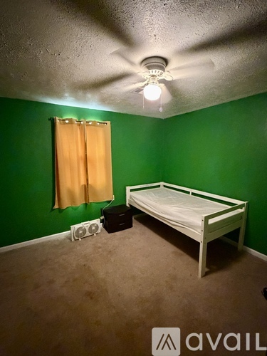 A bedroom with a bed, a window with curtains, and a ceiling fan.