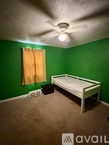 A bedroom with a bed, a window with curtains, and a ceiling fan.