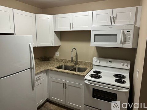 A kitchen with white appliances and cabinets.