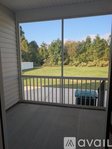 A balcony with a view of a green lawn and trees.