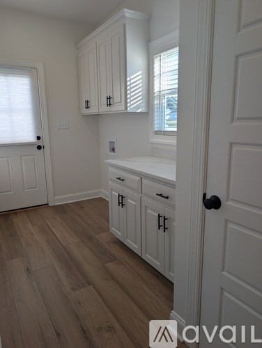 A kitchen with white cabinets and a wooden floor.