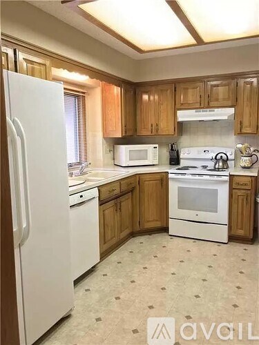 A kitchen with white appliances and wooden cabinets.
