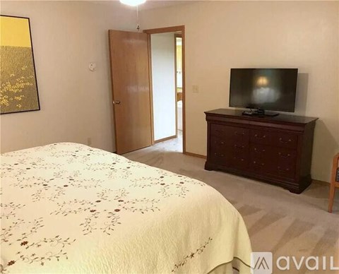 A bedroom with a bed, a television, and a door.