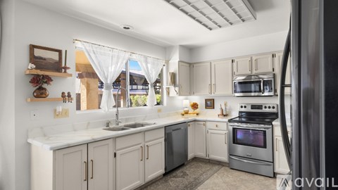 A kitchen with white cabinets and a stainless steel refrigerator.