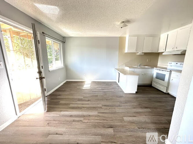 A kitchen with white appliances and wooden floors.