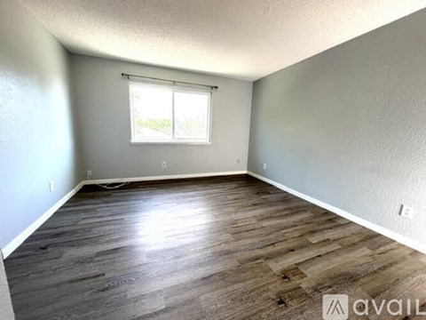 A room with wooden flooring and a window with blinds.