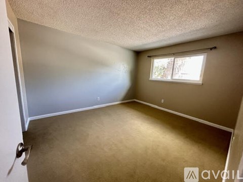 A room with a window and a door is available for rent.