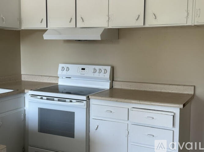 A kitchen with white cabinets and a stove top oven.