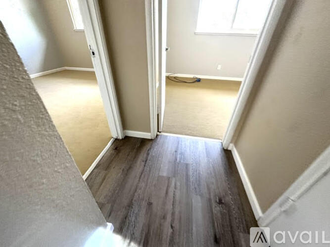A hallway with a wooden floor and white walls.