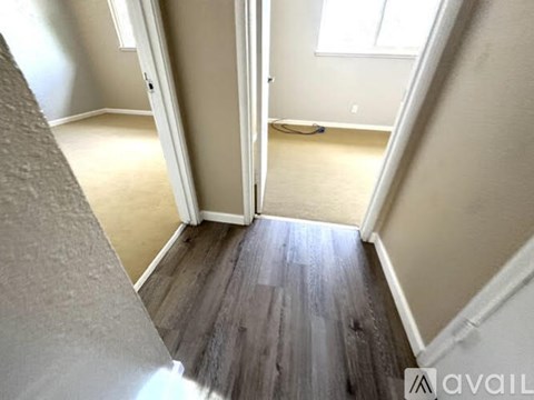 A hallway with a wooden floor and white walls.