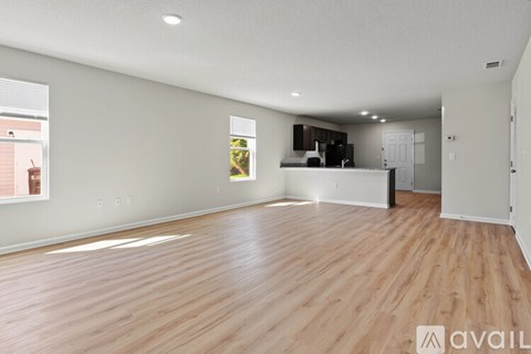 A spacious room with wooden flooring and a large window.