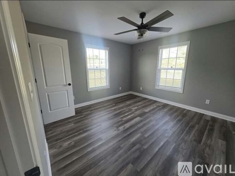 A room with a ceiling fan and two windows.