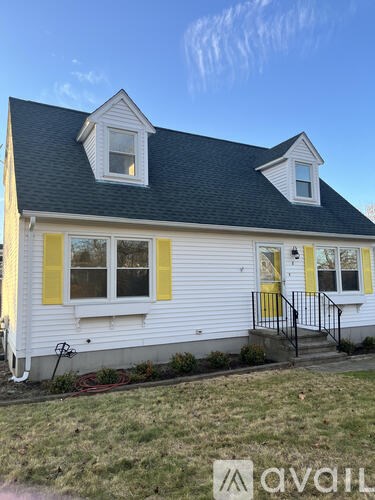A white house with yellow trim and a black roof.