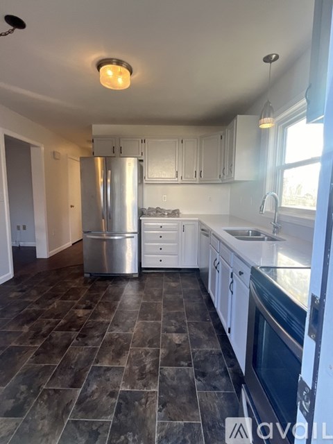 A kitchen with a refrigerator, sink, and cabinets.