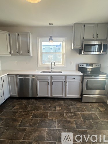 A kitchen with a sink, stove, and cabinets.