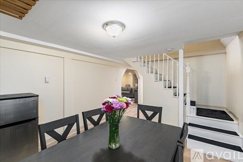 A dining room with a table, chairs, and a vase of flowers.