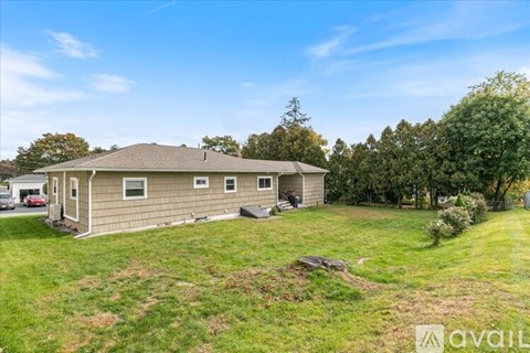 A house with a large lawn and trees in the background.