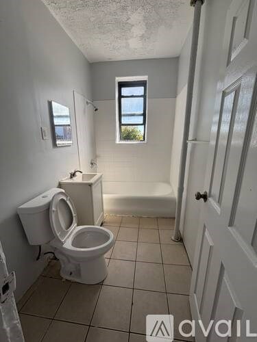 A white toilet is in a small bathroom with a window.
