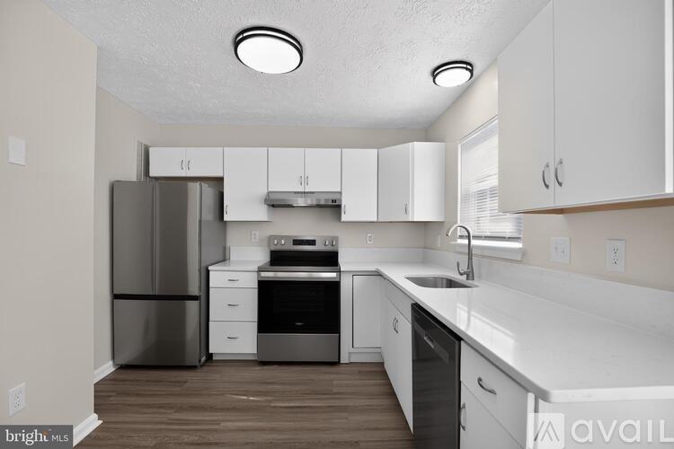 A kitchen with white cabinets and a stainless steel refrigerator.