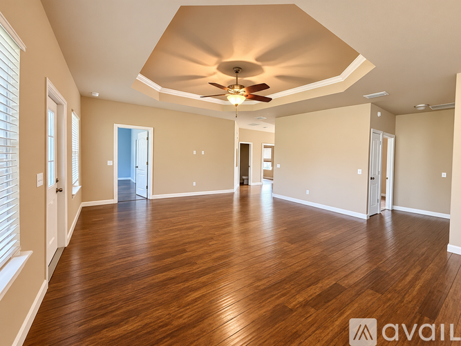 A spacious room with wooden flooring and a ceiling fan.
