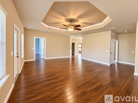A spacious room with wooden flooring and a ceiling fan.