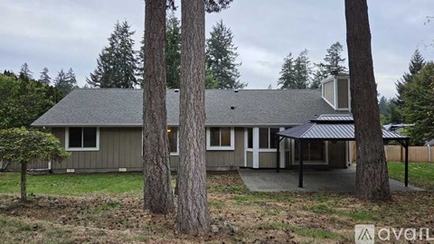 A house with a grey roof and a porch surrounded by trees.