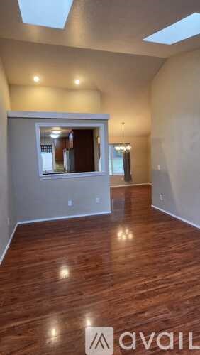 A spacious room with wooden floors and skylights.