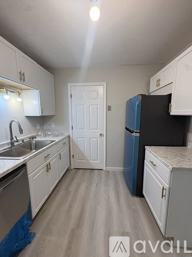 A kitchen with white cabinets and a black fridge.