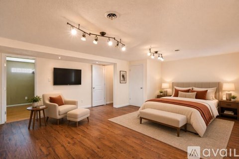 A bedroom with a large bed and a television on the wall.