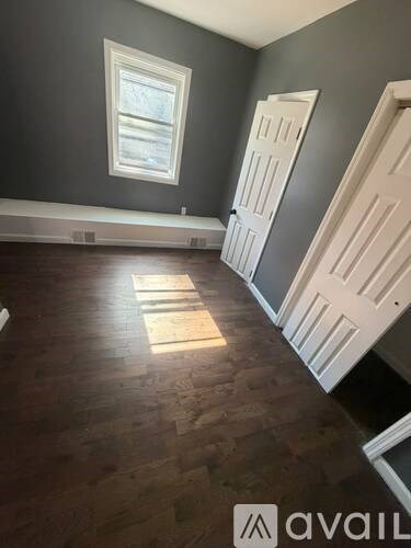 A room with wooden floors and a window letting in sunlight.
