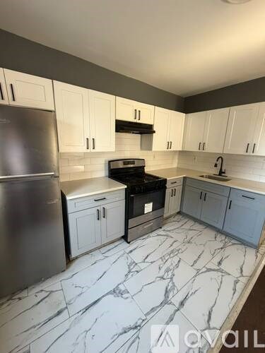 A kitchen with a marble floor and white cabinets.
